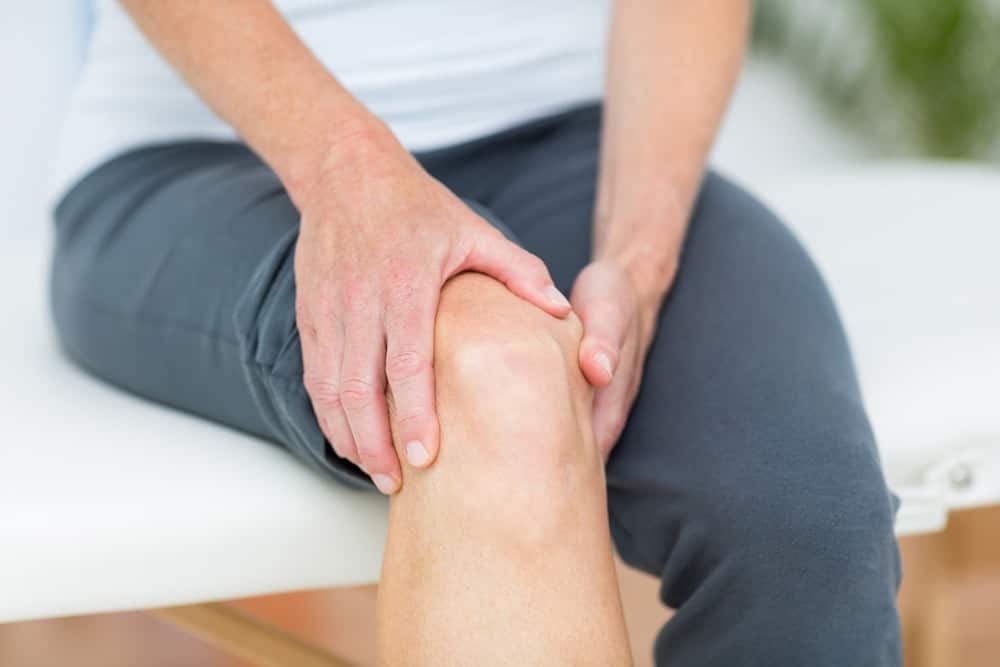 male patient holding his knee due to pain