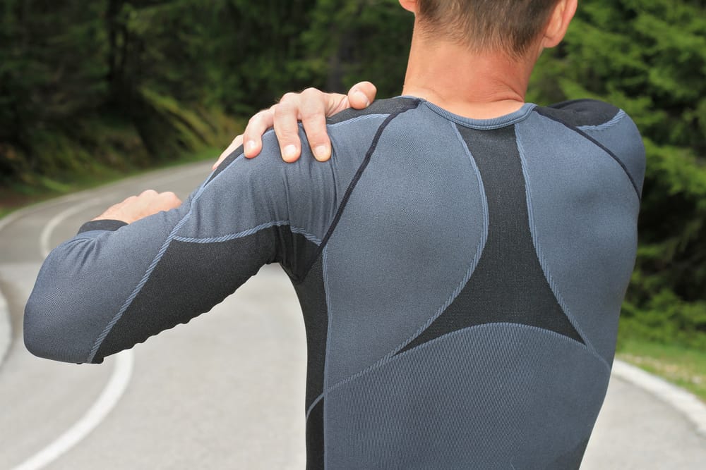 athletic guy holding his shoulder due to arthritis pain.