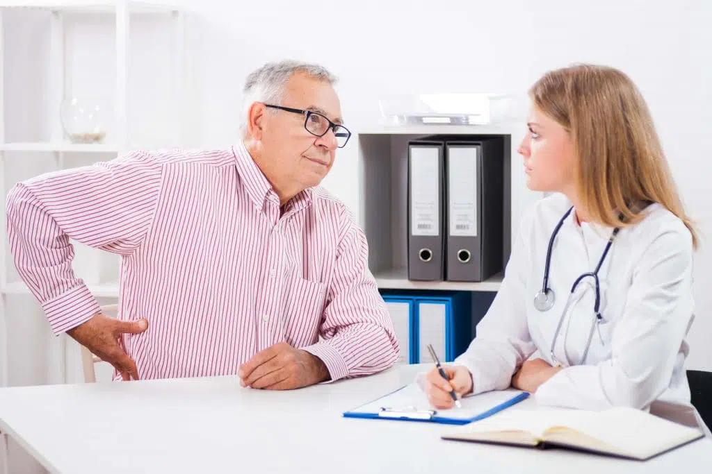 Older male patient speaking to his doctor about hip pain