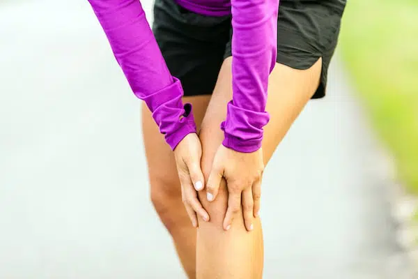 Woman holding her knee due to pain after running.