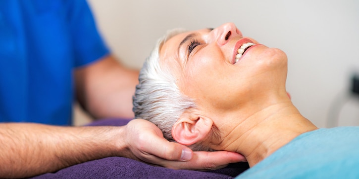 chiropractor massaging female patients neck