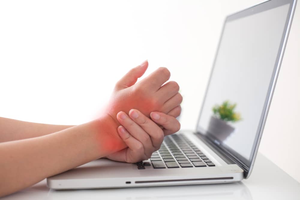 Osteoarthritis in the hand of woman typing at a computer