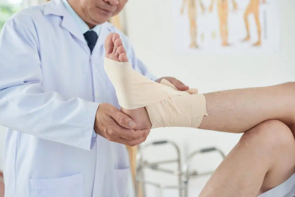 Doctor wrapping a bandage across a patients ankle.