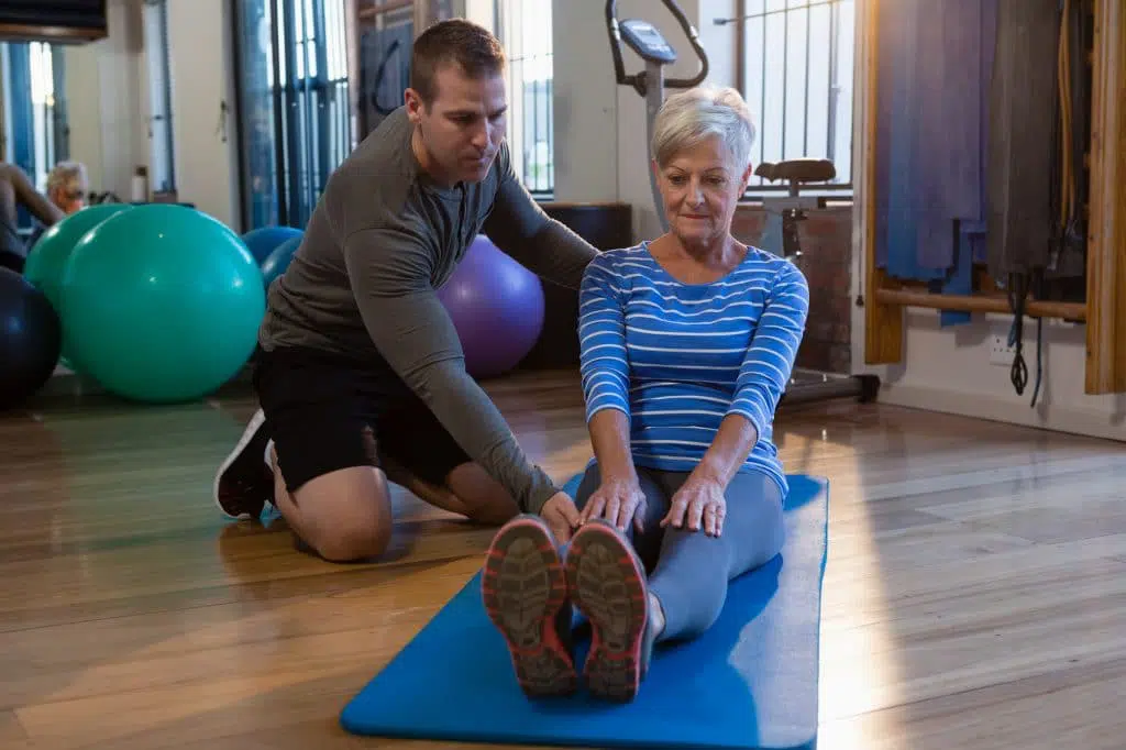 Physical therapist helping his female patient stretch.
