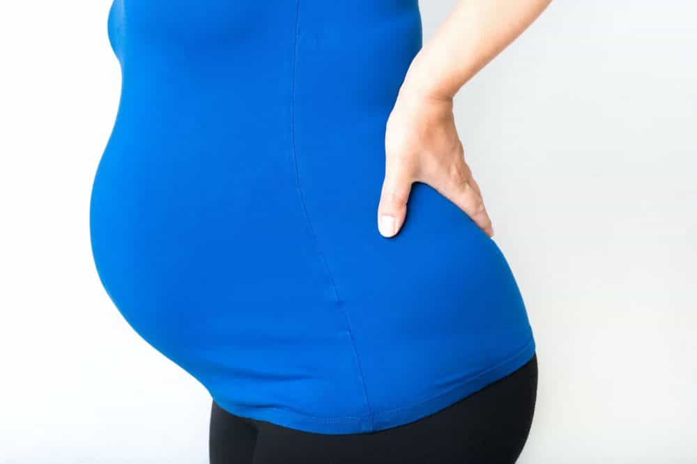 Pregnant woman holding hands on her back,
