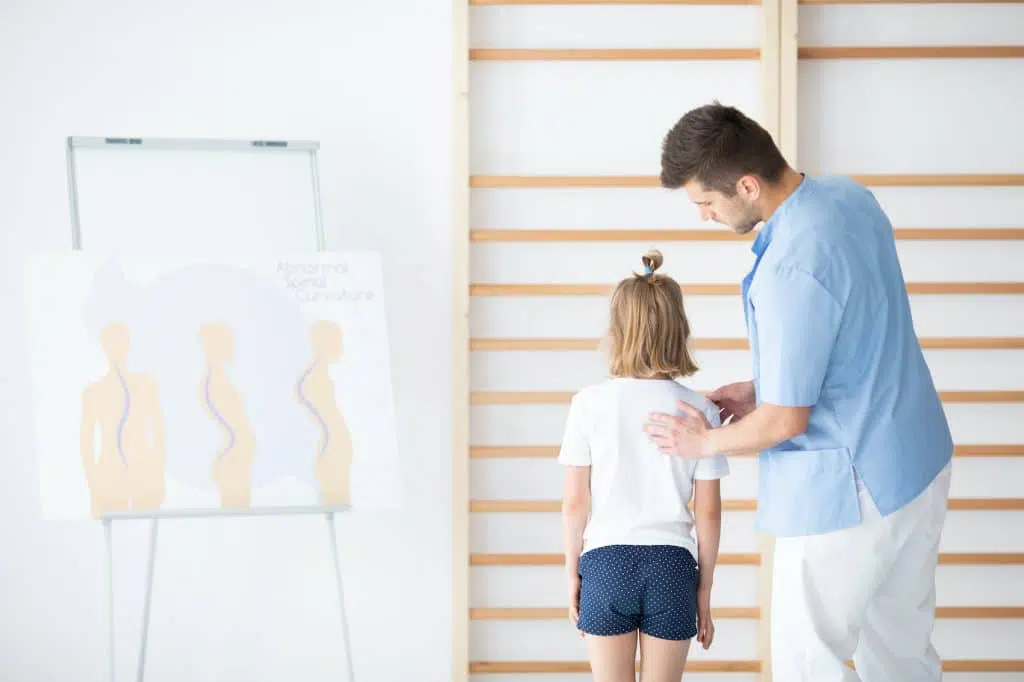 Doctor measuring the back of a girl with scoliosis