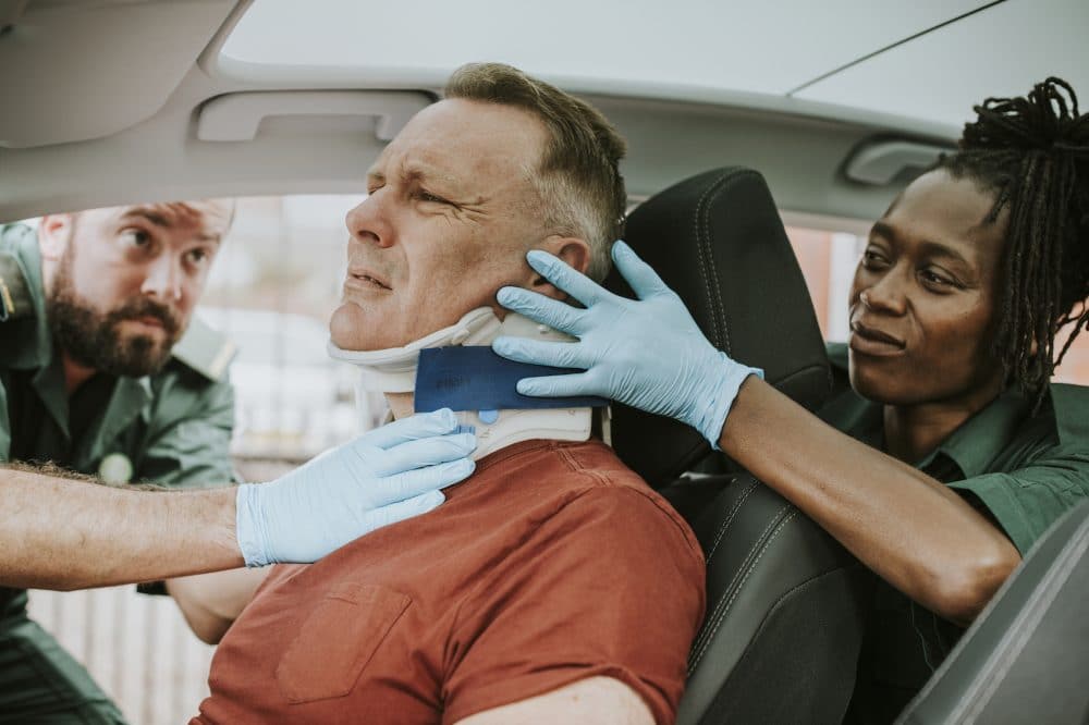 paramedics placing a neck brace on a motorist involved in a car accident