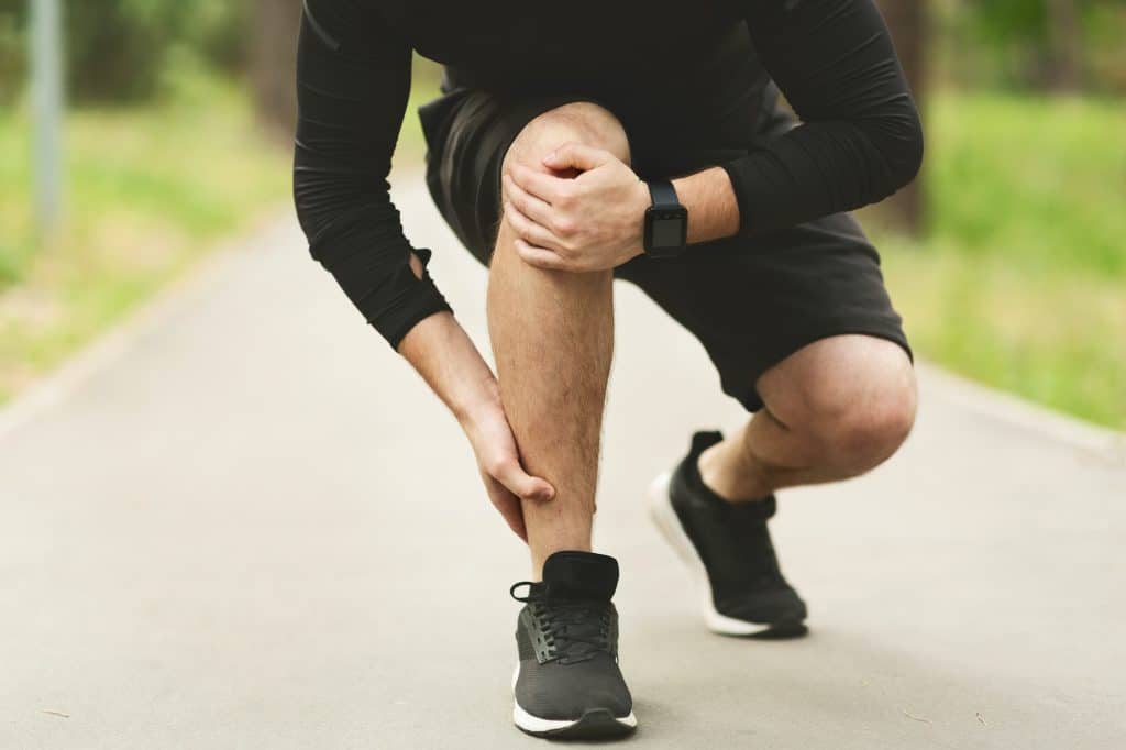 Male runner holding his foot due to pain