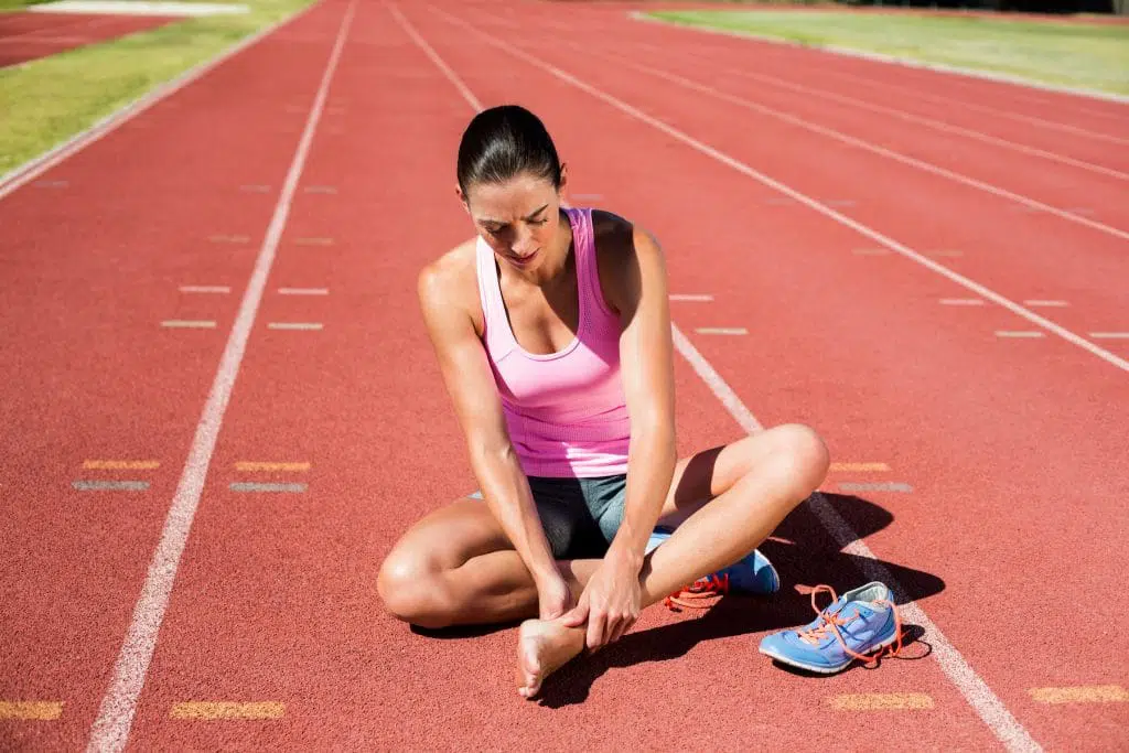 Young girl sitting on the ground due to a hurt foot.