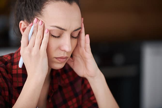 Female having migraine attacks while working.