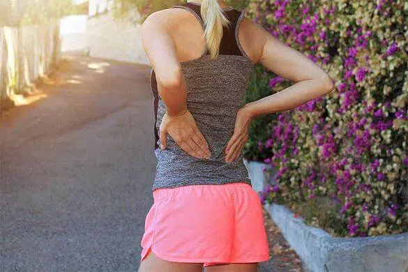 Young female runner having backache caused by spondylolisthesis or spondylolysis.