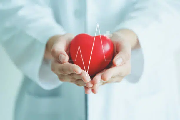 Doctor holding a red heart shape in his hand, showing health insurance concept